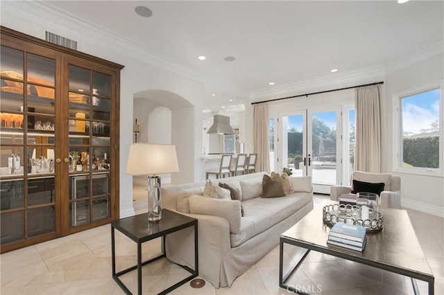 living room with plenty of natural light, crown molding, and french doors