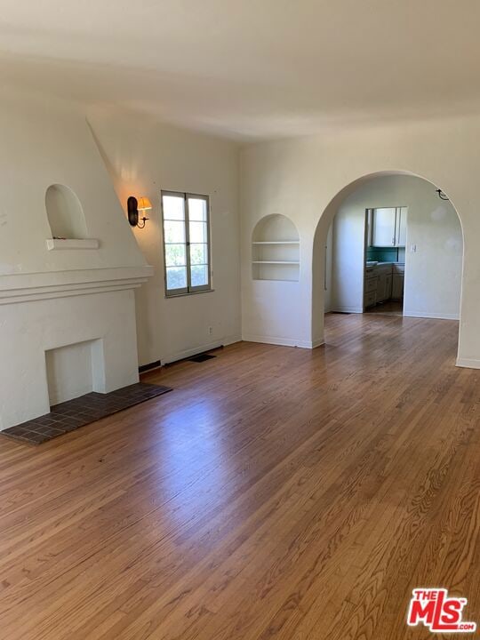 unfurnished room with built in features and hardwood / wood-style flooring