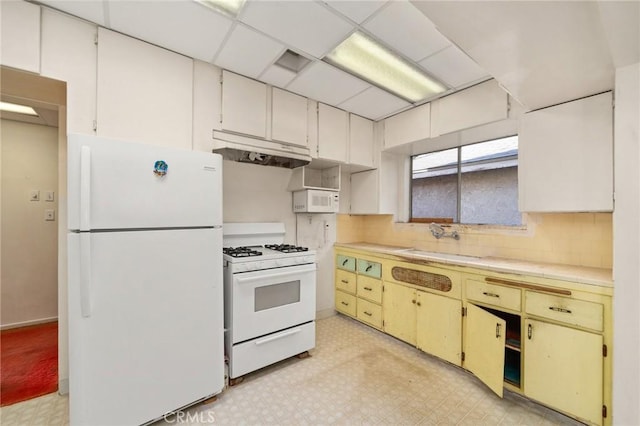 kitchen featuring a paneled ceiling, white cabinetry, sink, and white appliances