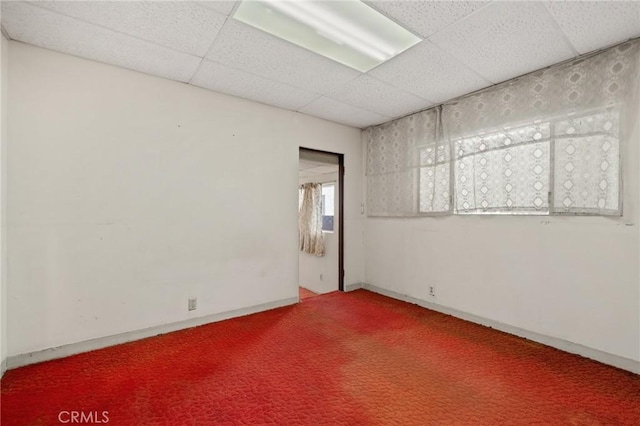 carpeted empty room with a drop ceiling