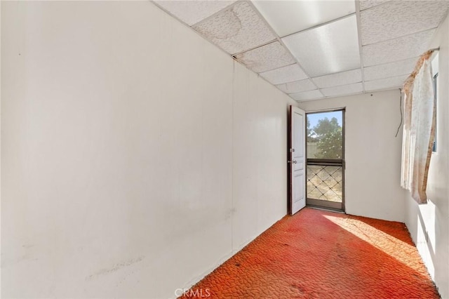 carpeted empty room with a drop ceiling