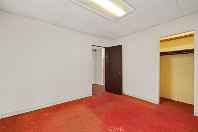 unfurnished bedroom featuring carpet flooring, a paneled ceiling, and a closet