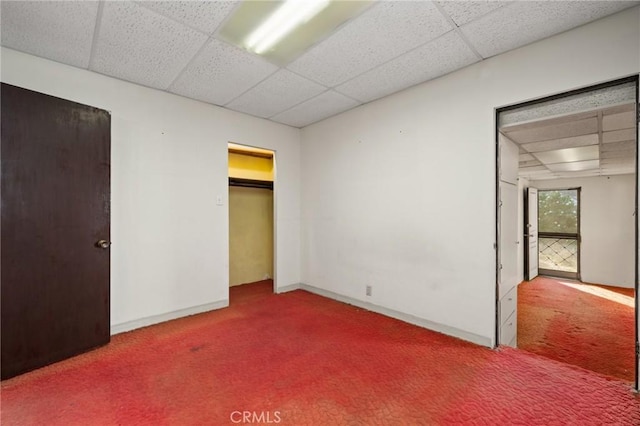 unfurnished bedroom featuring carpet flooring, a paneled ceiling, and a closet