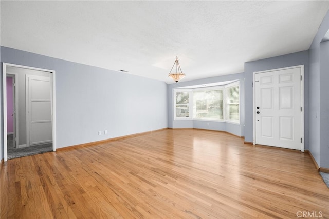 unfurnished living room with light wood-type flooring and a textured ceiling