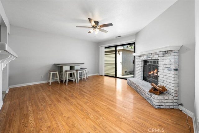 unfurnished living room with ceiling fan, light hardwood / wood-style flooring, and a brick fireplace