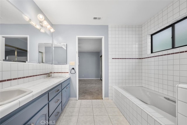 bathroom with tile patterned floors, tiled bath, and vanity