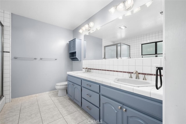 bathroom featuring tile patterned floors, toilet, decorative backsplash, vanity, and a shower with shower door