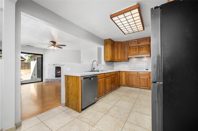 kitchen with ceiling fan, sink, kitchen peninsula, a fireplace, and appliances with stainless steel finishes