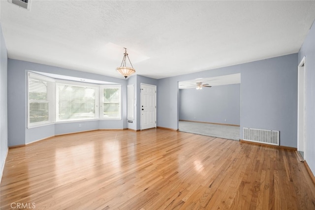 empty room featuring a textured ceiling, light hardwood / wood-style flooring, and ceiling fan