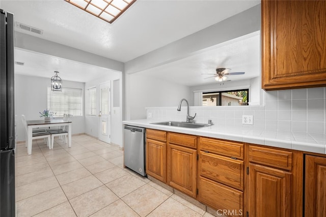 kitchen with dishwasher, backsplash, ceiling fan with notable chandelier, sink, and light tile patterned floors