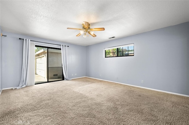 empty room with carpet flooring, ceiling fan, and a textured ceiling