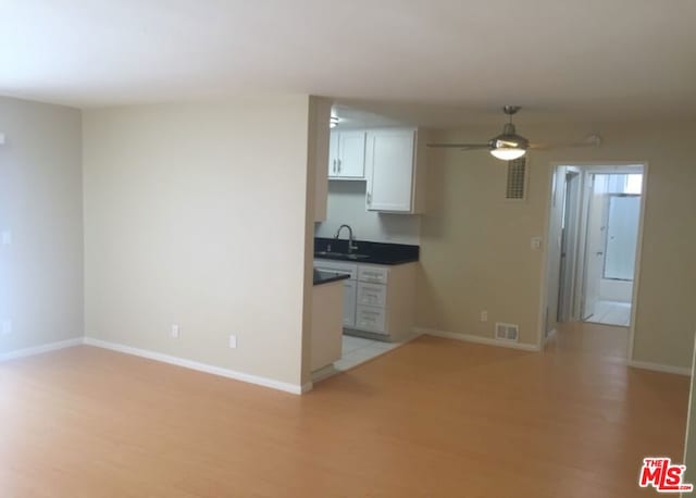 kitchen featuring ceiling fan, sink, white cabinets, and light hardwood / wood-style flooring