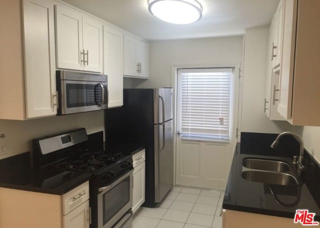 kitchen with white cabinets, light tile patterned flooring, sink, and appliances with stainless steel finishes