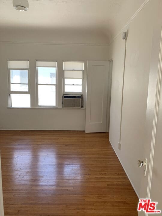 spare room with crown molding, cooling unit, and dark wood-type flooring