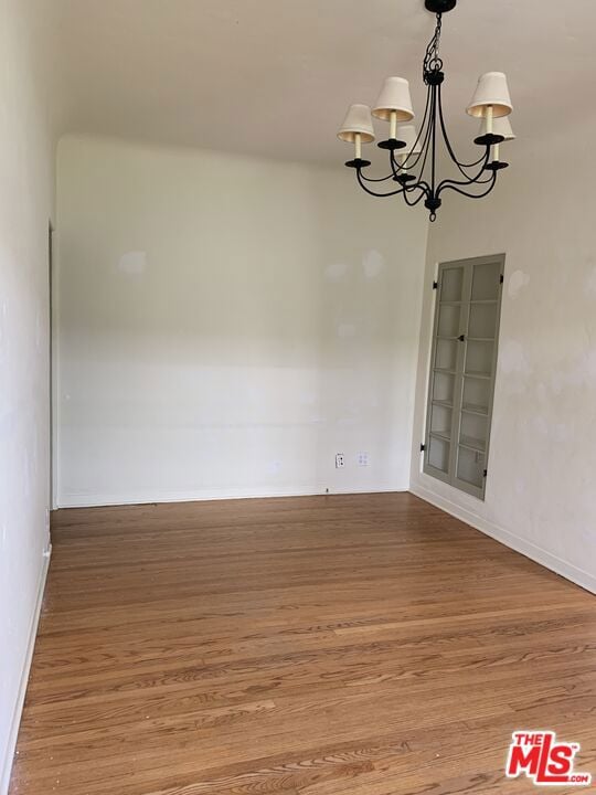 empty room featuring a notable chandelier and hardwood / wood-style flooring