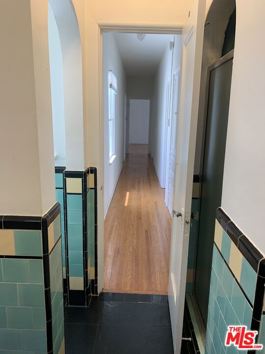 corridor with dark hardwood / wood-style flooring and tile walls