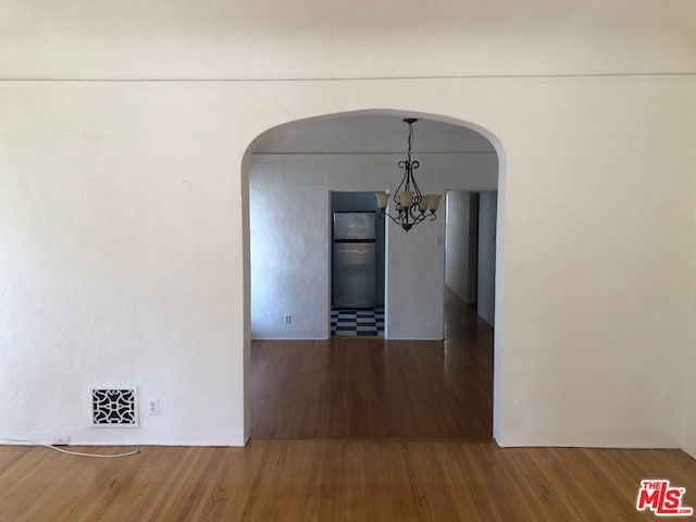 corridor featuring an inviting chandelier and hardwood / wood-style flooring