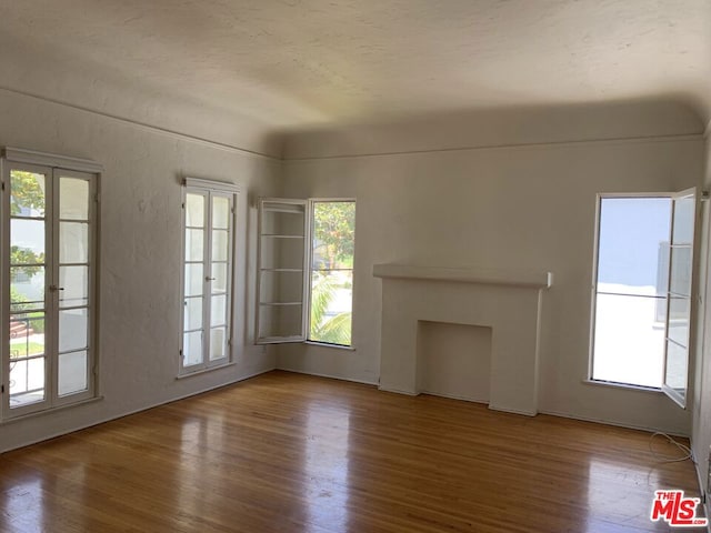 unfurnished living room featuring hardwood / wood-style flooring and plenty of natural light