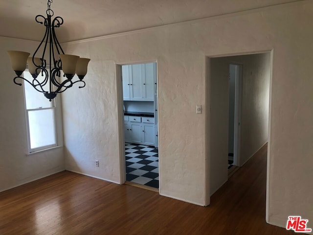 unfurnished dining area featuring a chandelier and dark hardwood / wood-style flooring