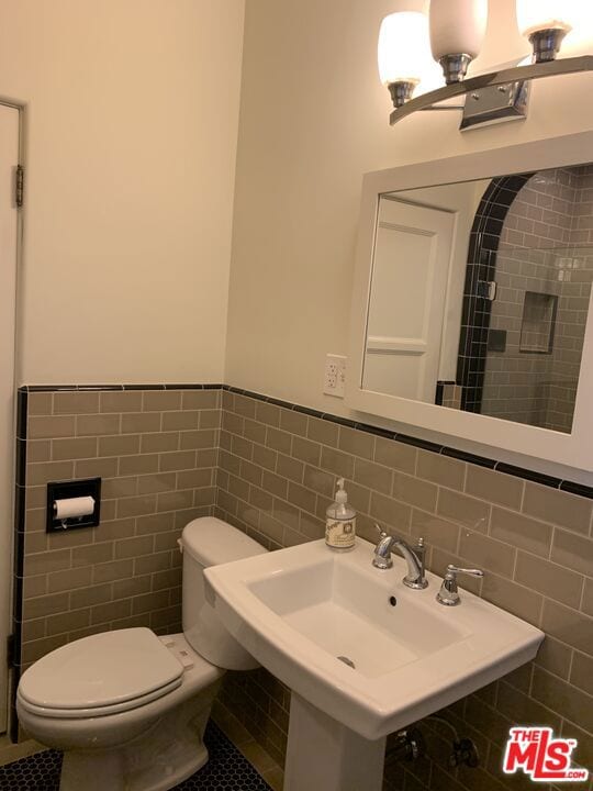 bathroom featuring sink, toilet, tile walls, and tile patterned floors