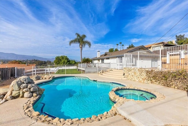 view of swimming pool with a mountain view and an in ground hot tub