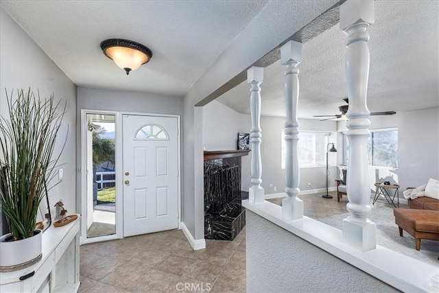 foyer with a textured ceiling, decorative columns, and ceiling fan