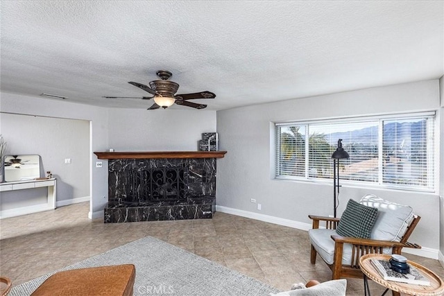 living room featuring a high end fireplace, a textured ceiling, and ceiling fan