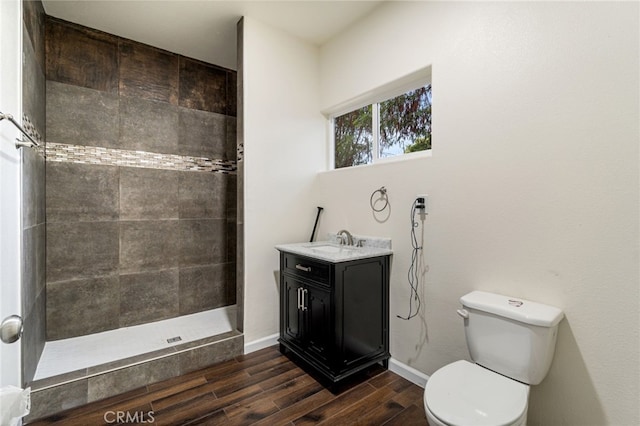 bathroom featuring a tile shower, toilet, vanity, and hardwood / wood-style flooring