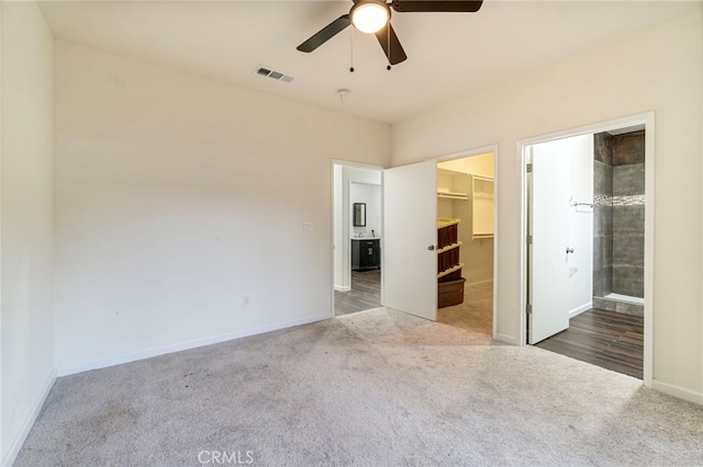 unfurnished bedroom with a walk in closet, connected bathroom, ceiling fan, carpet floors, and a closet