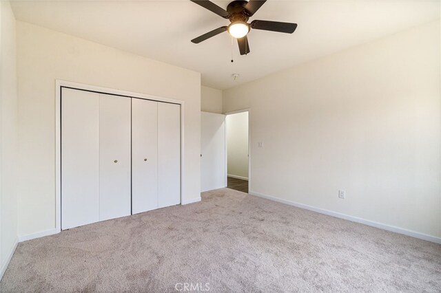 unfurnished bedroom featuring ceiling fan, a closet, and light carpet