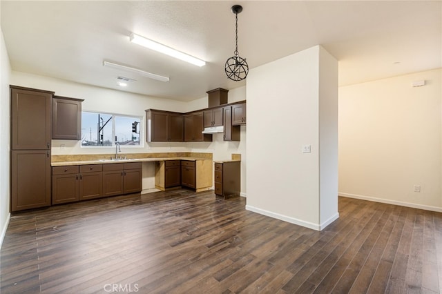 kitchen featuring pendant lighting, dark brown cabinets, dark wood-type flooring, and sink