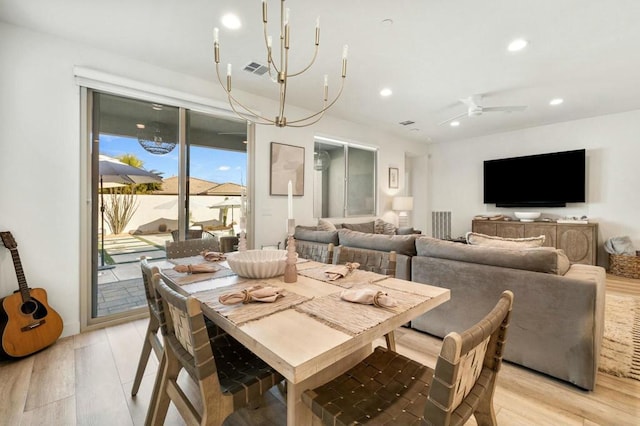 dining room with ceiling fan with notable chandelier and light hardwood / wood-style flooring