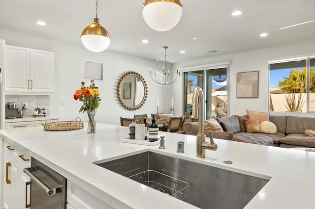 kitchen featuring white cabinetry, tasteful backsplash, hanging light fixtures, and sink