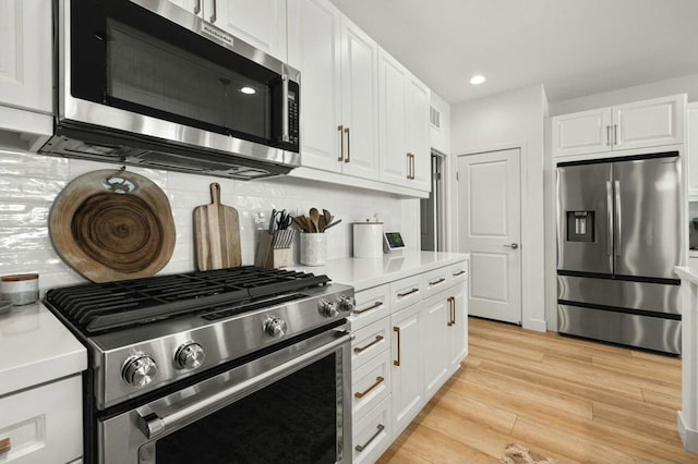 kitchen featuring tasteful backsplash, light wood-type flooring, appliances with stainless steel finishes, and white cabinetry