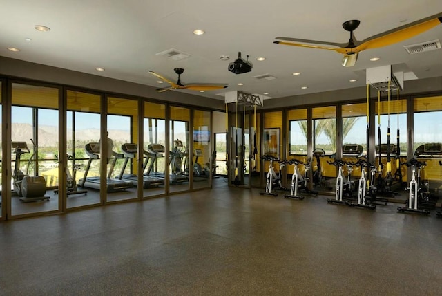 exercise room featuring ceiling fan, a mountain view, and a healthy amount of sunlight