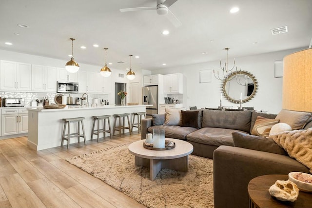 living room with ceiling fan, light wood-type flooring, and sink