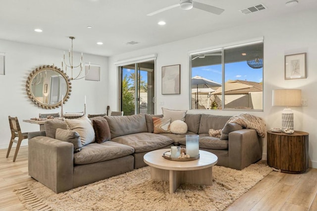 living room featuring ceiling fan with notable chandelier, light hardwood / wood-style floors, and plenty of natural light