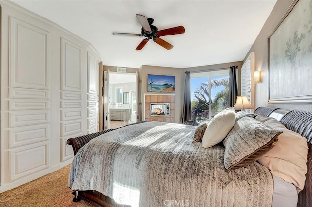 carpeted bedroom with access to exterior, ceiling fan, a fireplace, and ensuite bathroom