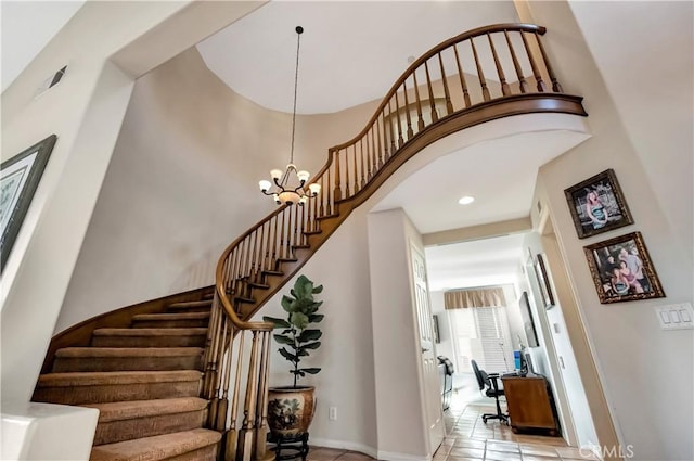 staircase featuring tile patterned flooring, a towering ceiling, and a notable chandelier