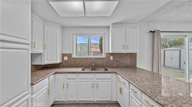 kitchen featuring white cabinets, decorative backsplash, and sink