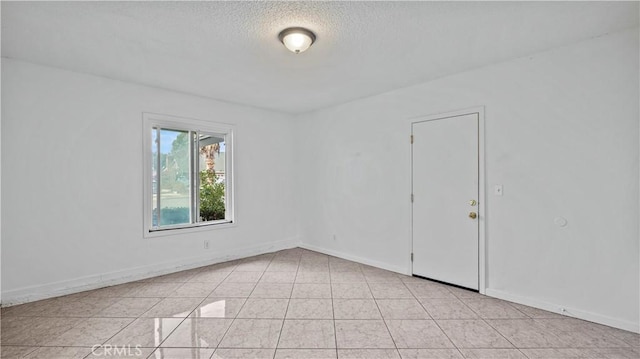 spare room with light tile patterned floors and a textured ceiling