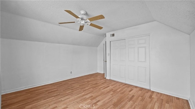 bonus room featuring a textured ceiling, light wood-type flooring, ceiling fan, and lofted ceiling