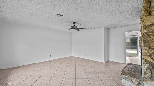 empty room featuring ceiling fan, light tile patterned floors, and a textured ceiling