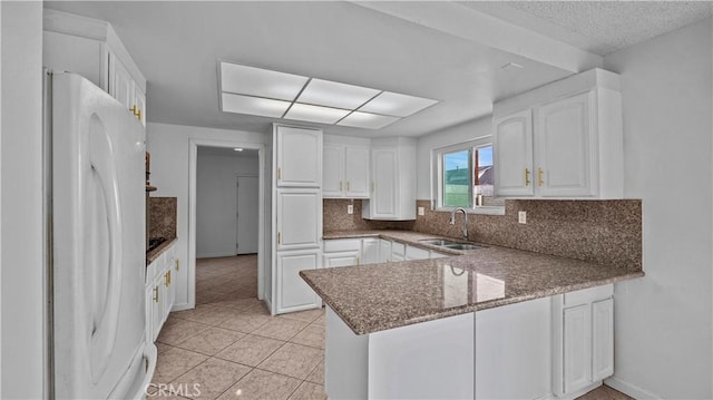 kitchen with sink, tasteful backsplash, white refrigerator, kitchen peninsula, and white cabinets