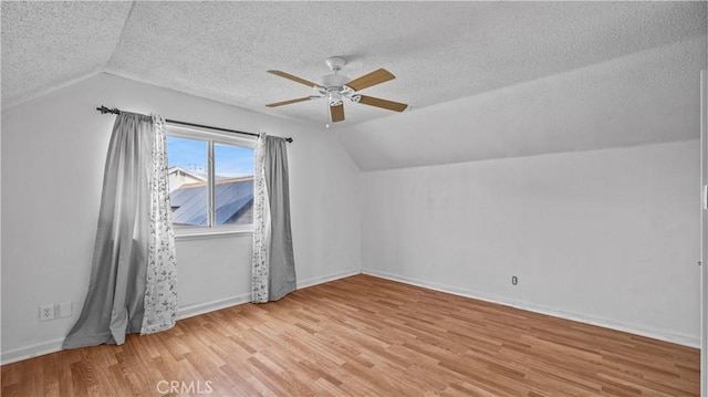 additional living space featuring ceiling fan, lofted ceiling, a textured ceiling, and light hardwood / wood-style flooring