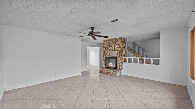 unfurnished living room featuring a fireplace, light tile patterned floors, and a textured ceiling