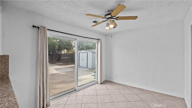 tiled spare room with a textured ceiling and ceiling fan