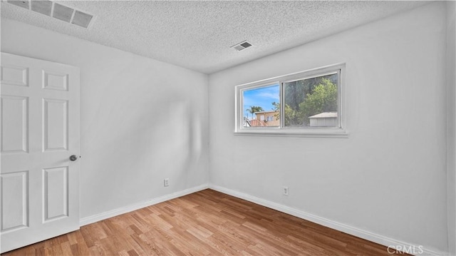 spare room with a textured ceiling and light hardwood / wood-style flooring