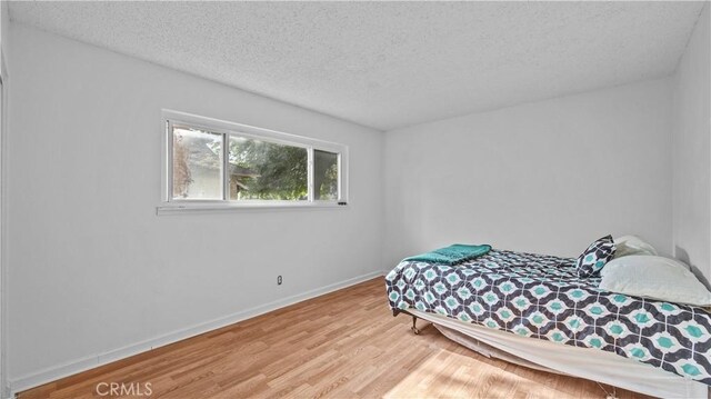 bedroom featuring light hardwood / wood-style flooring and a textured ceiling