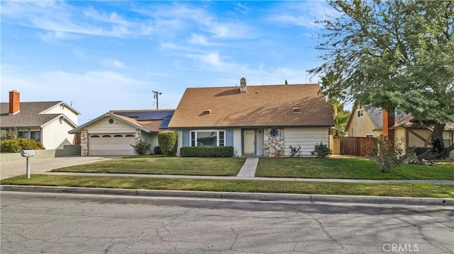 ranch-style house with solar panels, a garage, and a front lawn